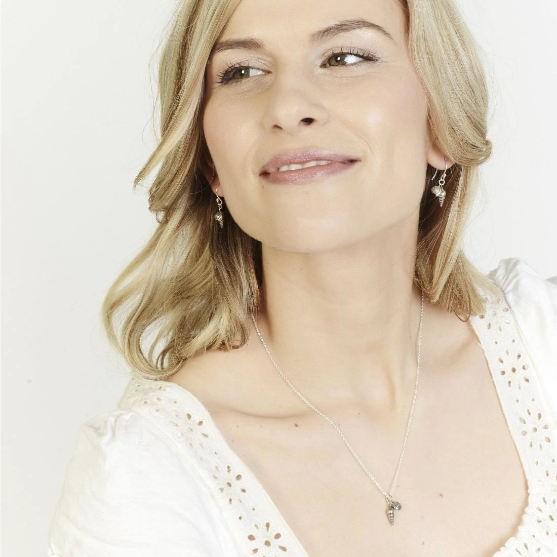 Smiling model wearing the double shell pendant in sterling silver with matching double shell drop earrings.