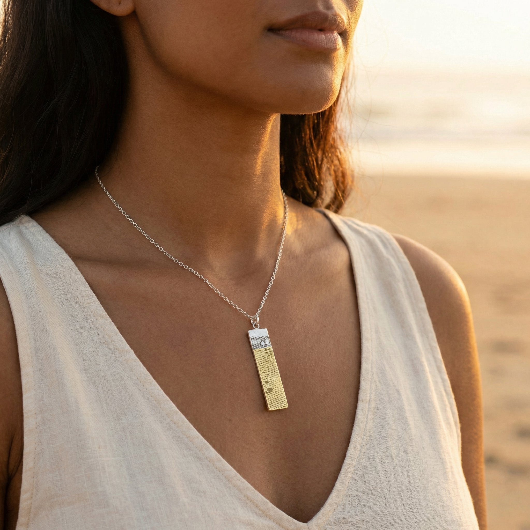 Model wearing the Footprints in the Sand Necklace, showing the sterling silver pendant with golden footprints.