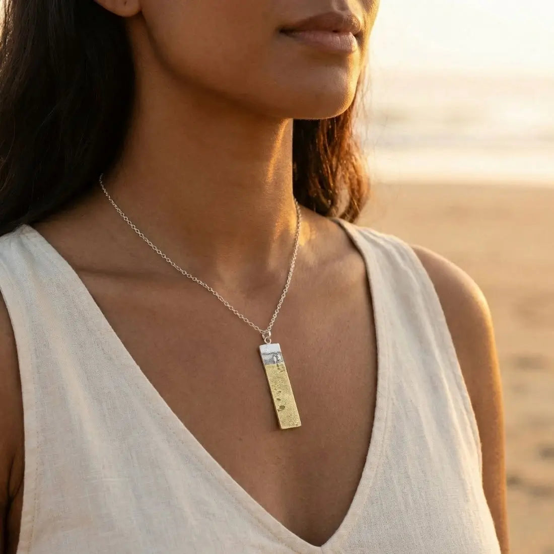 Model wearing the Footprints in the Sand Necklace, showing the sterling silver pendant with golden footprints.