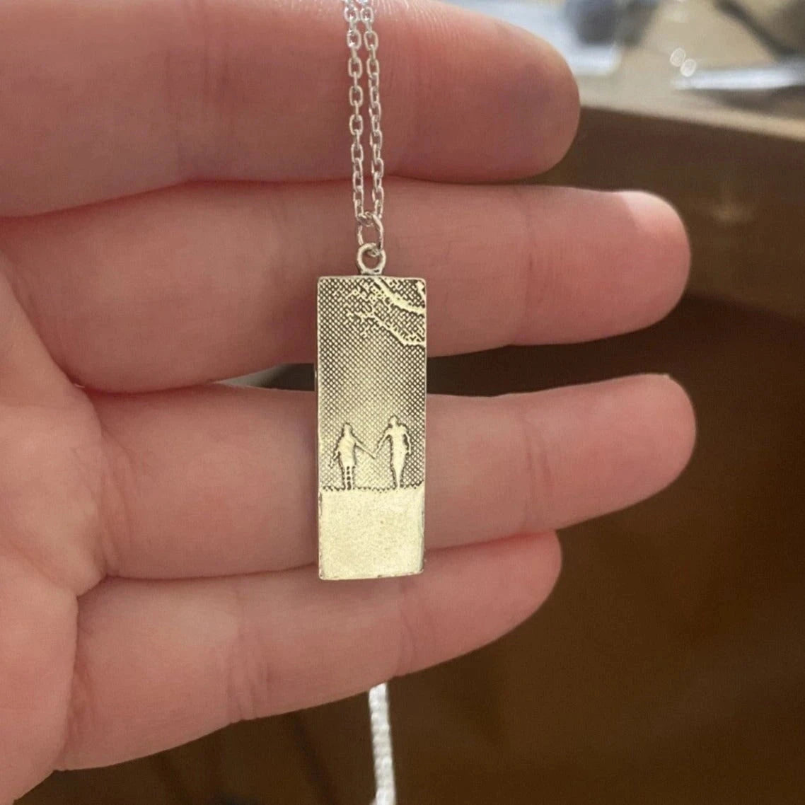 Close-up of the Hand in Hand Couple Necklace showing the polished sterling silver silhouette detail.