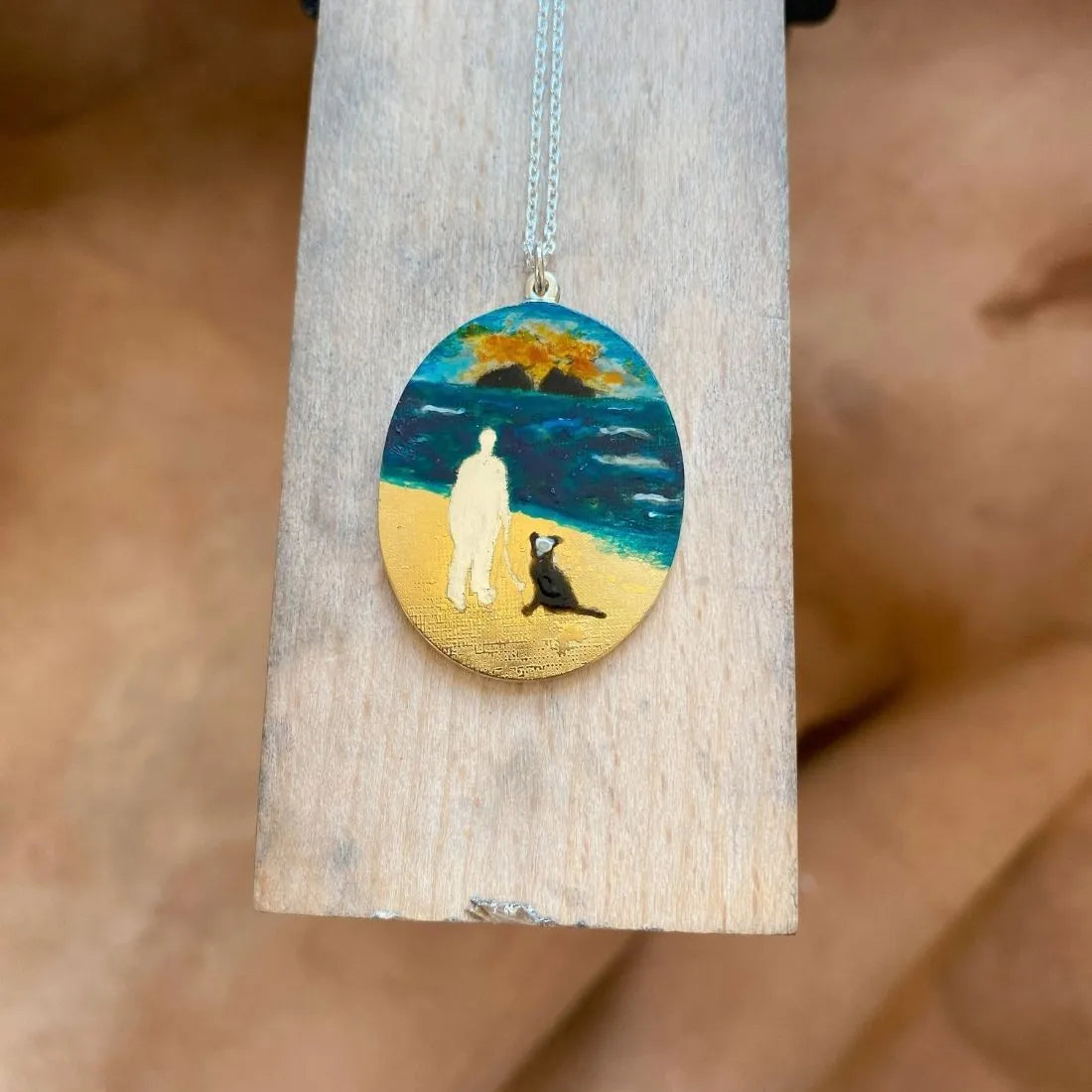 Enamel and gold vermeil miniature painting on necklace displayed on jewellers bench.