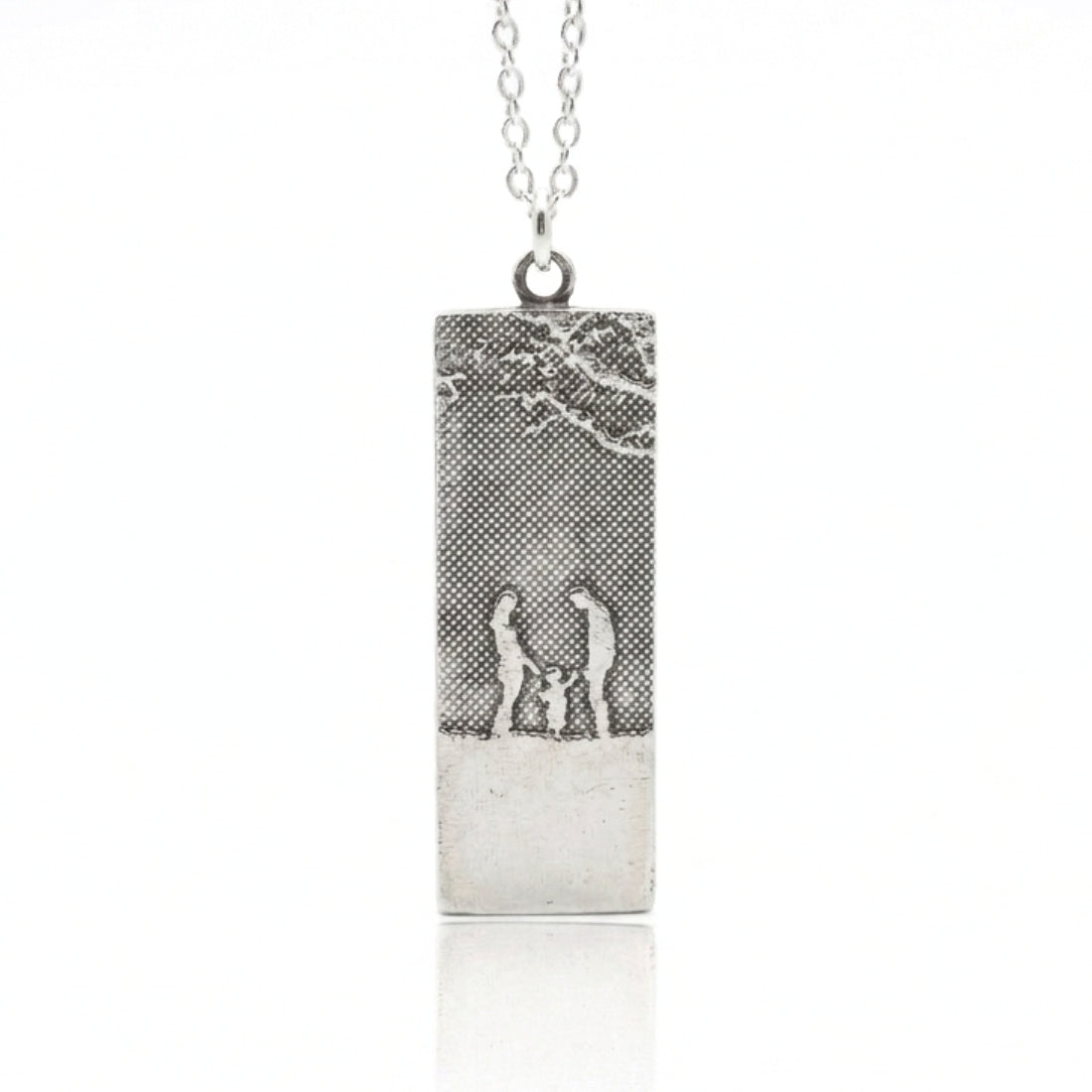 Our Little Family Necklace in sterling silver featuring a mother, father and child silhouette beneath tree branches.