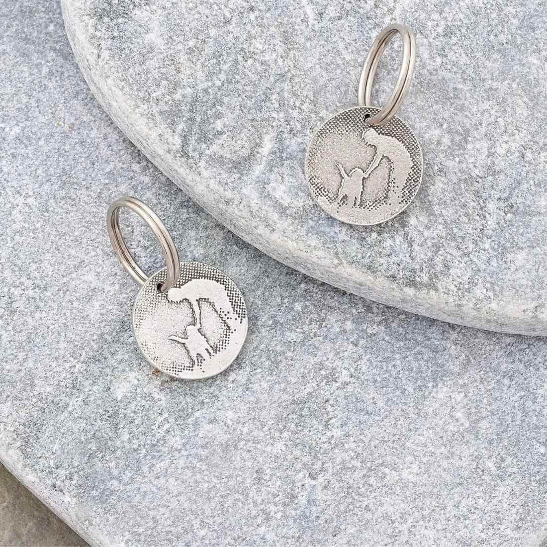 Personalised dog ID tags laid flat on a natural stone background.