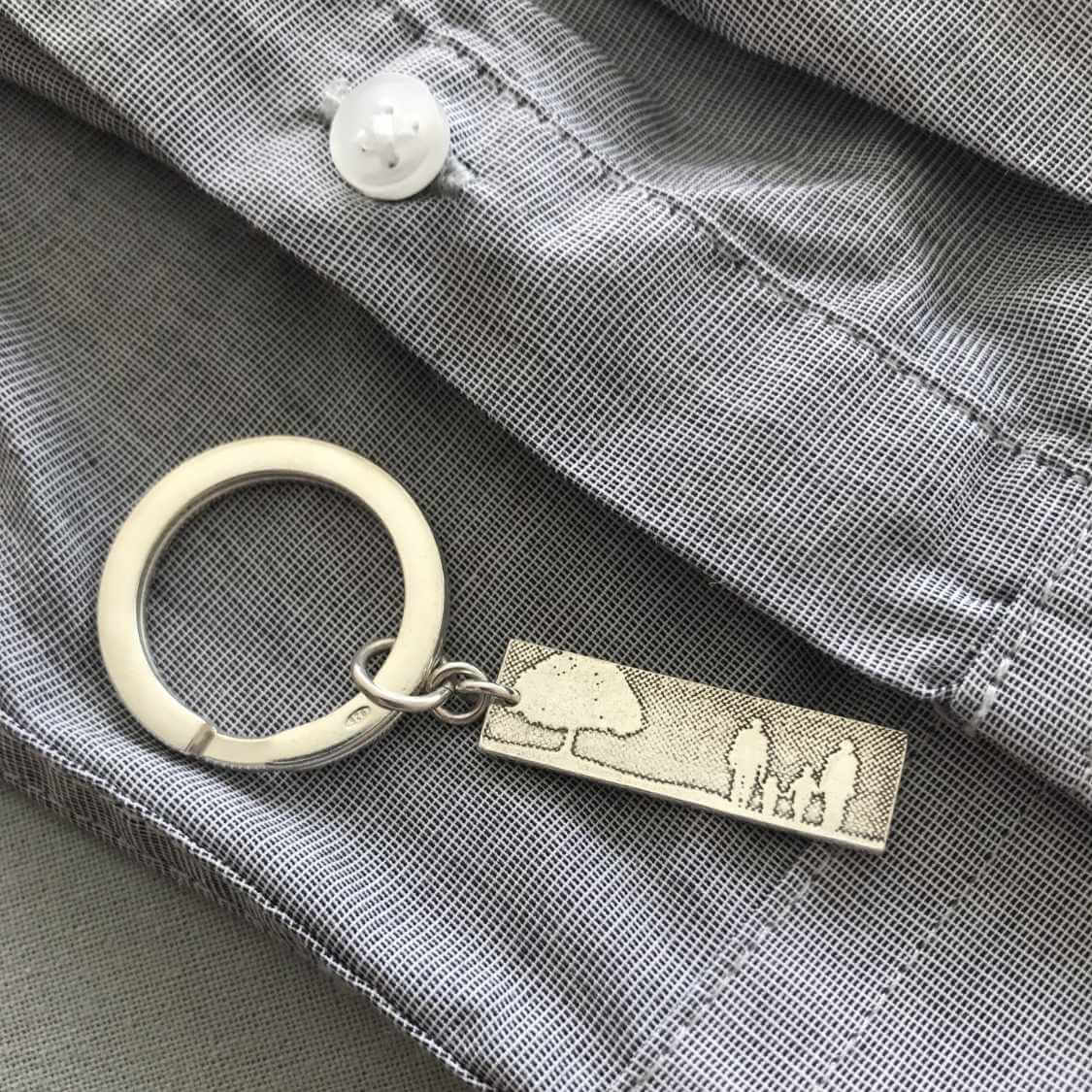Sterling silver family tree keyring laid on mans shirt.