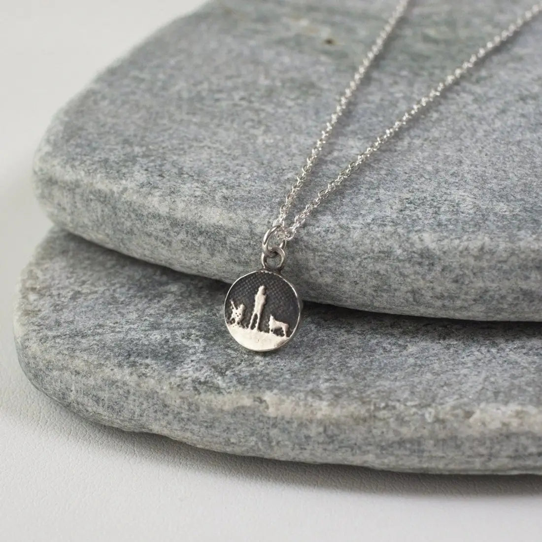 Lifestyle photo showing the Walks Under Night’s Sky Silver Dog Charm with two silver dogs displayed on a silver chain beneath an oxidised night sky.