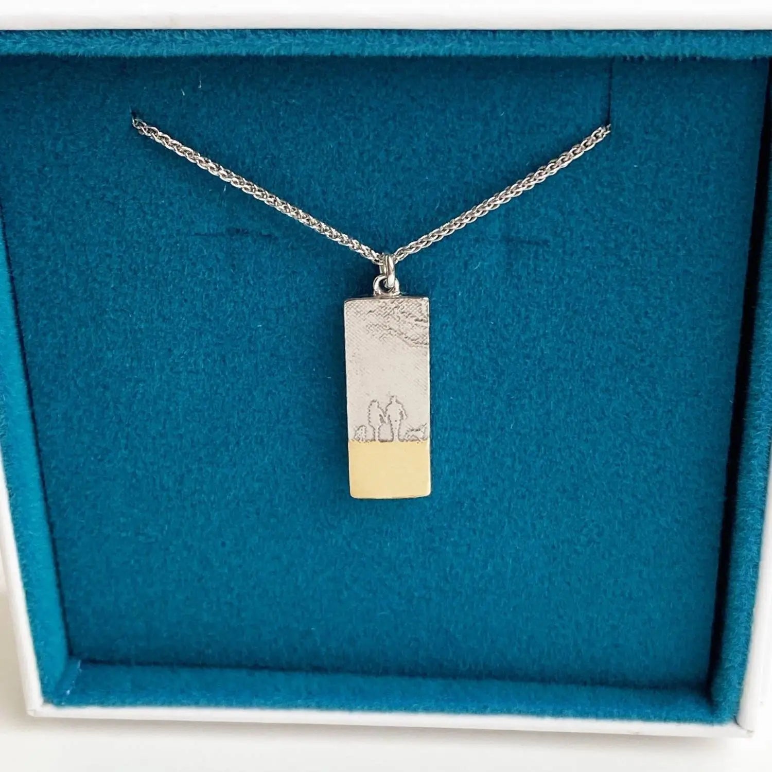 White gold couple and two dogs necklace with golden beach detail highlighting the etched silhouette scene.