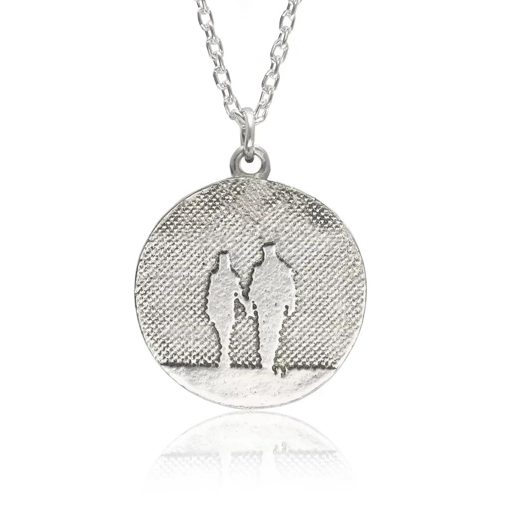 Round Silver Couple Necklace showing two figures enjoying a quiet moment together, etched into sterling silver with oxidised detail.