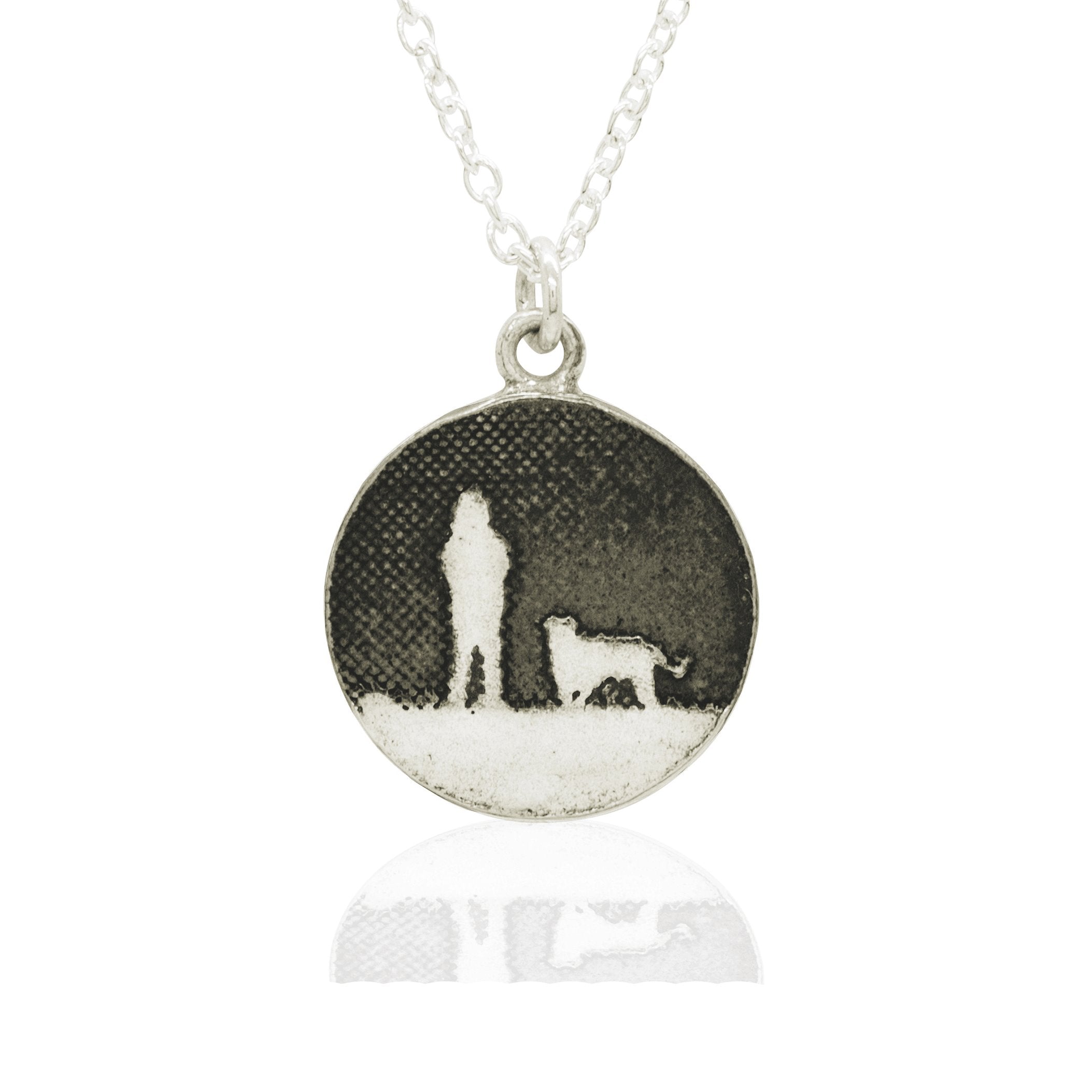 Sterling silver round dog necklace showing a person walking their dog under a moonlit night sky in silhouette.