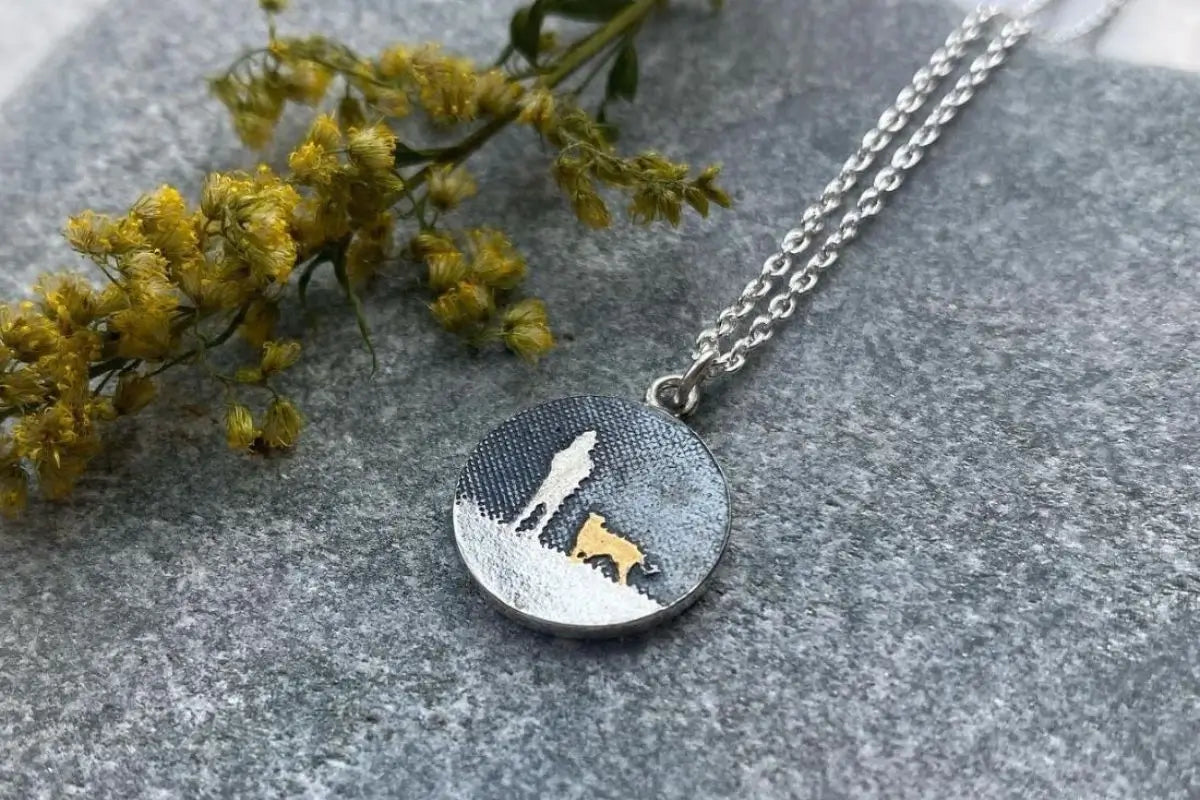 round pendant showing person and dog silhouette with gold dog detail