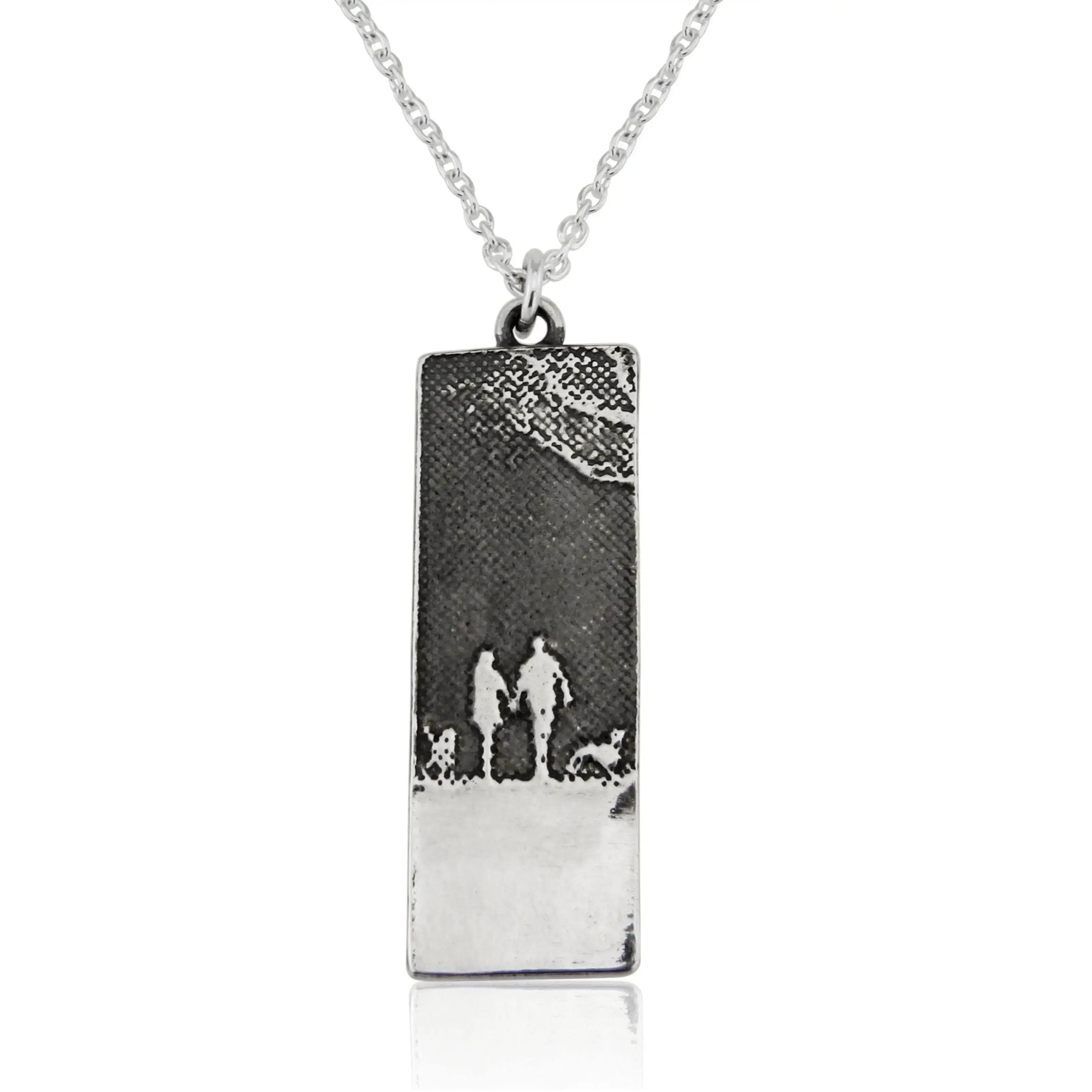 Night sky necklace featuring a couple and their two dogs in an etched silhouette beneath a moonlit sky.