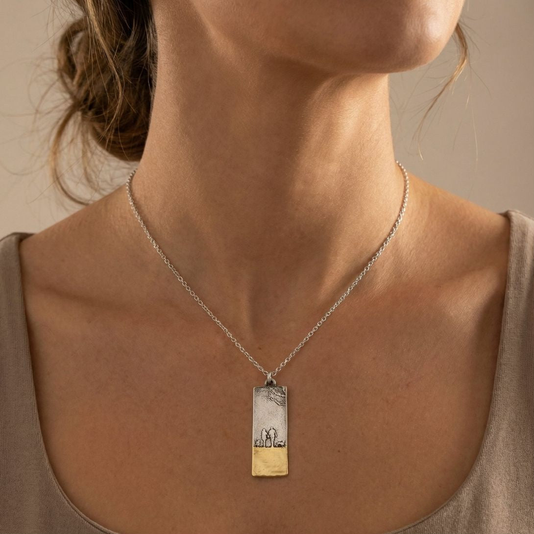Model wearing the Beach Memories Couple & Two Dogs Necklace inspired by seaside walks, showing the sterling silver silhouette pendant with gold shoreline detail.
