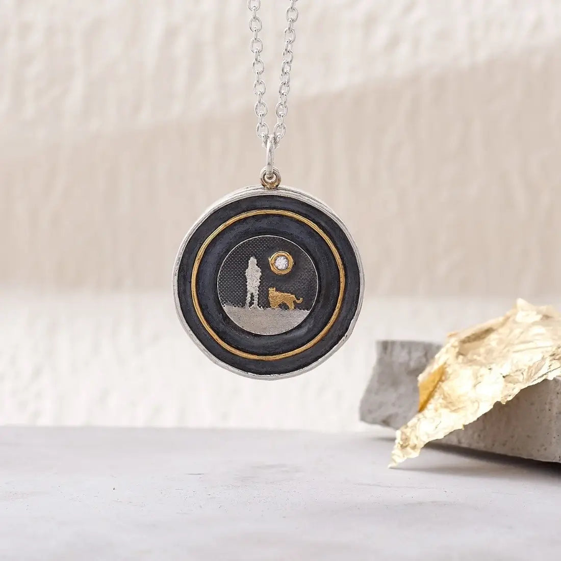 Dog Lovers Sapphire Moon Locket shown closed in a lifestyle setting with sterling silver dog silhouette and oxidised night sky.