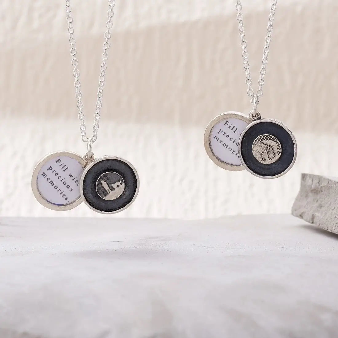 Lifestyle image showing two sterling silver dog lovers lockets open, with petting and standing silhouettes and visible photo frames.