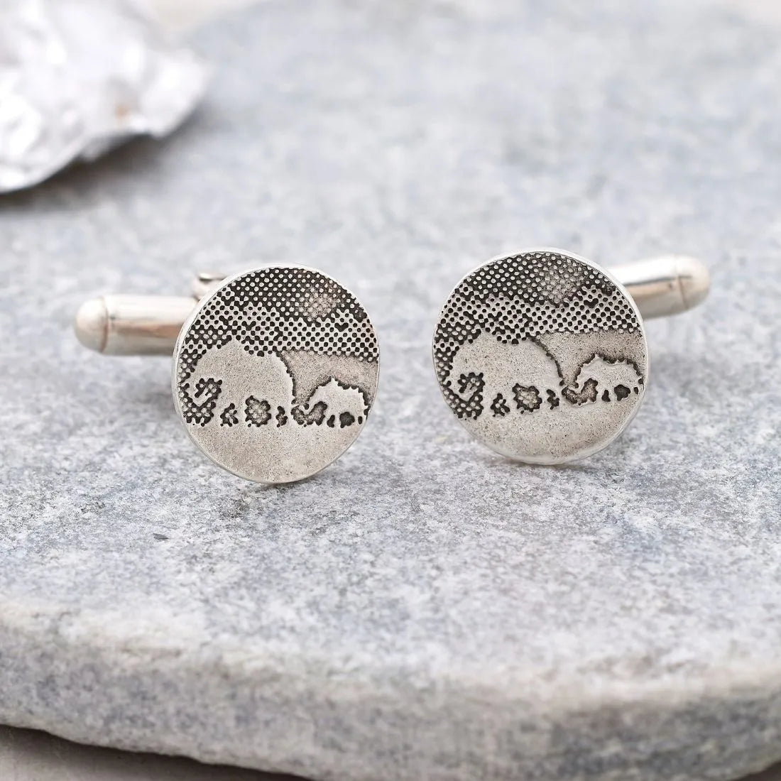 Elephant and little elephant cufflinks in sterling silver on natural grey stone background.