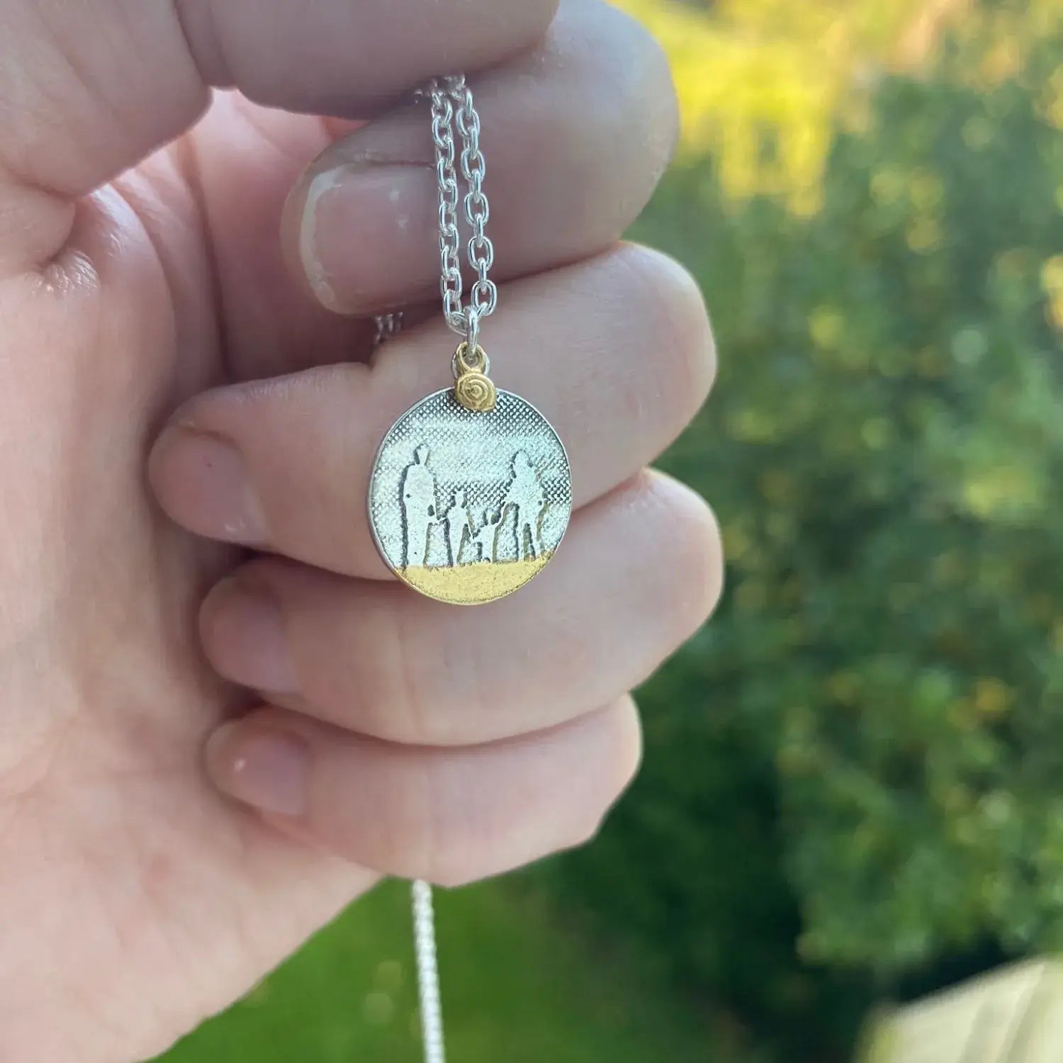 Hand holding a Beach Memories family necklace with a silver shell charm.