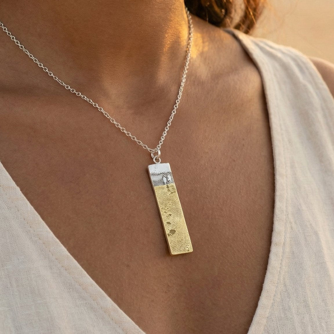 Model wearing the Footprints in the Sand Necklace, showing the sterling silver pendant with golden footprints.