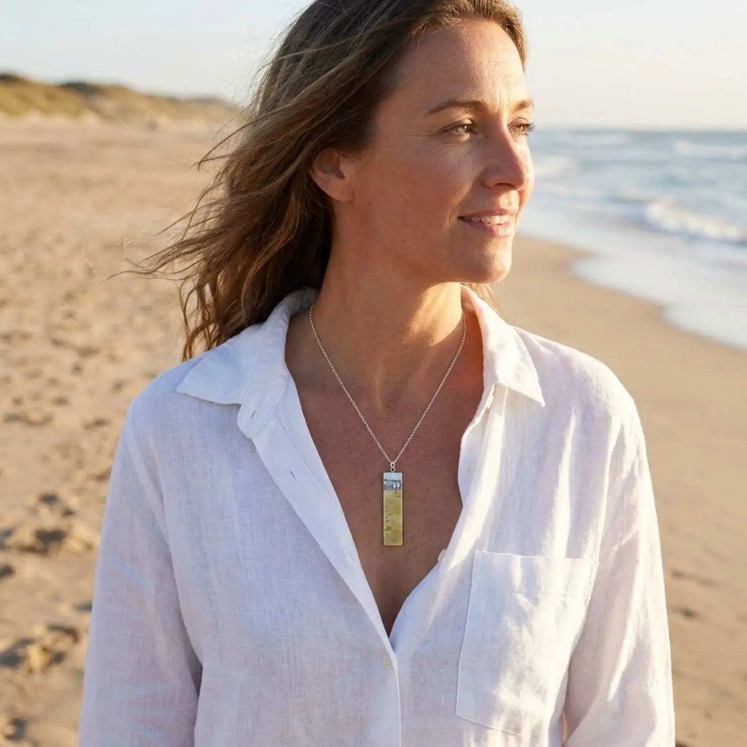 Model wearing a Footprints in the Sand memory necklace while standing on the beach.
