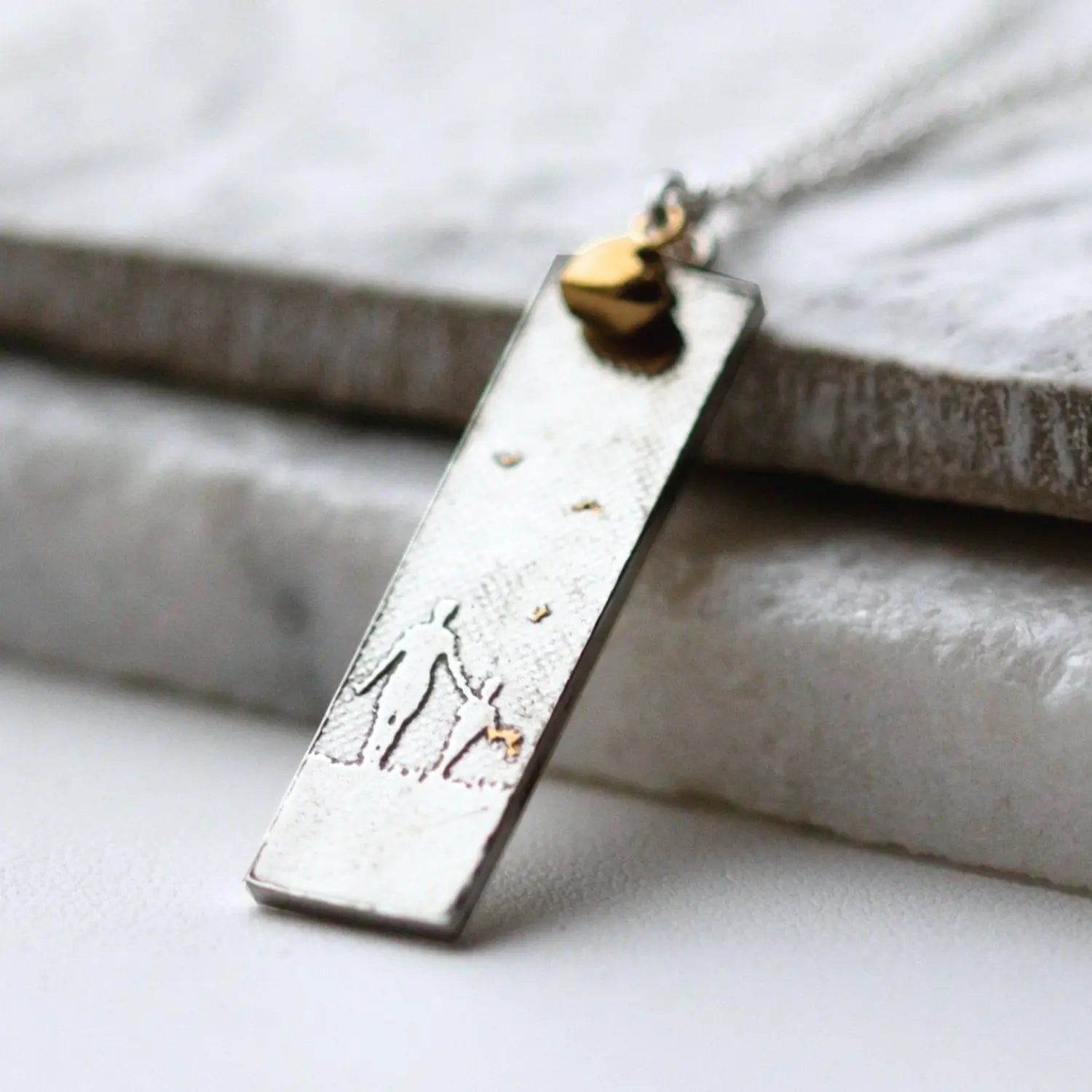 mother and child rectangle necklace with golden details against tile background