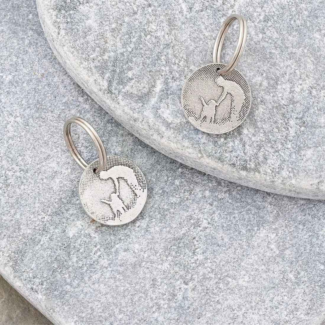 Personalised dog ID tags laid flat on a natural stone background.