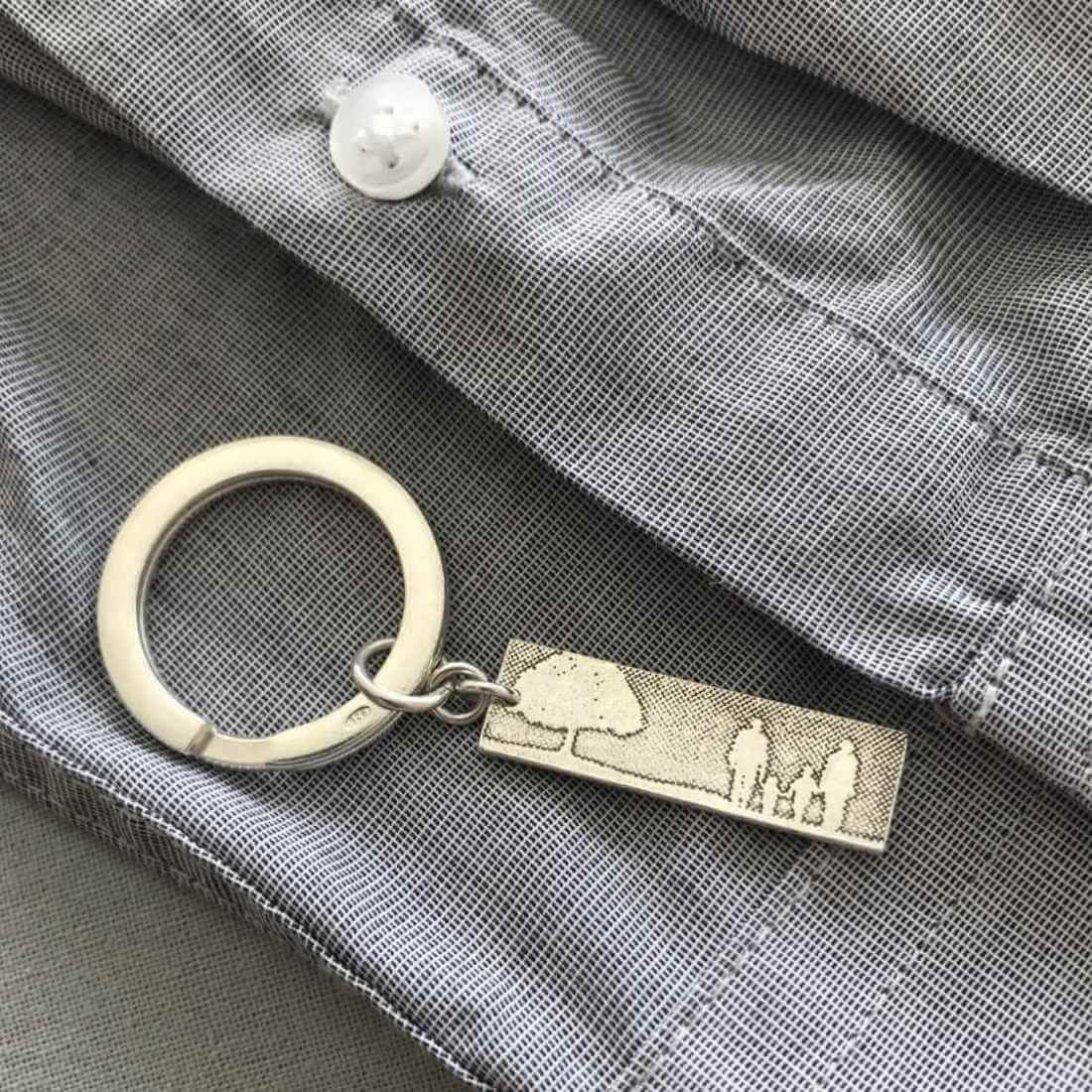 Sterling silver family tree keyring laid on mans shirt.