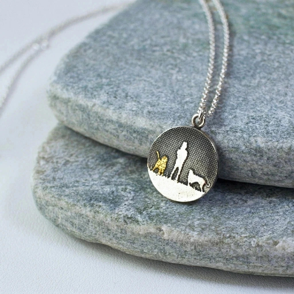 Two Dogs Night’s Sky Necklace displayed on a natural background showing the etched person and two dogs silhouette.