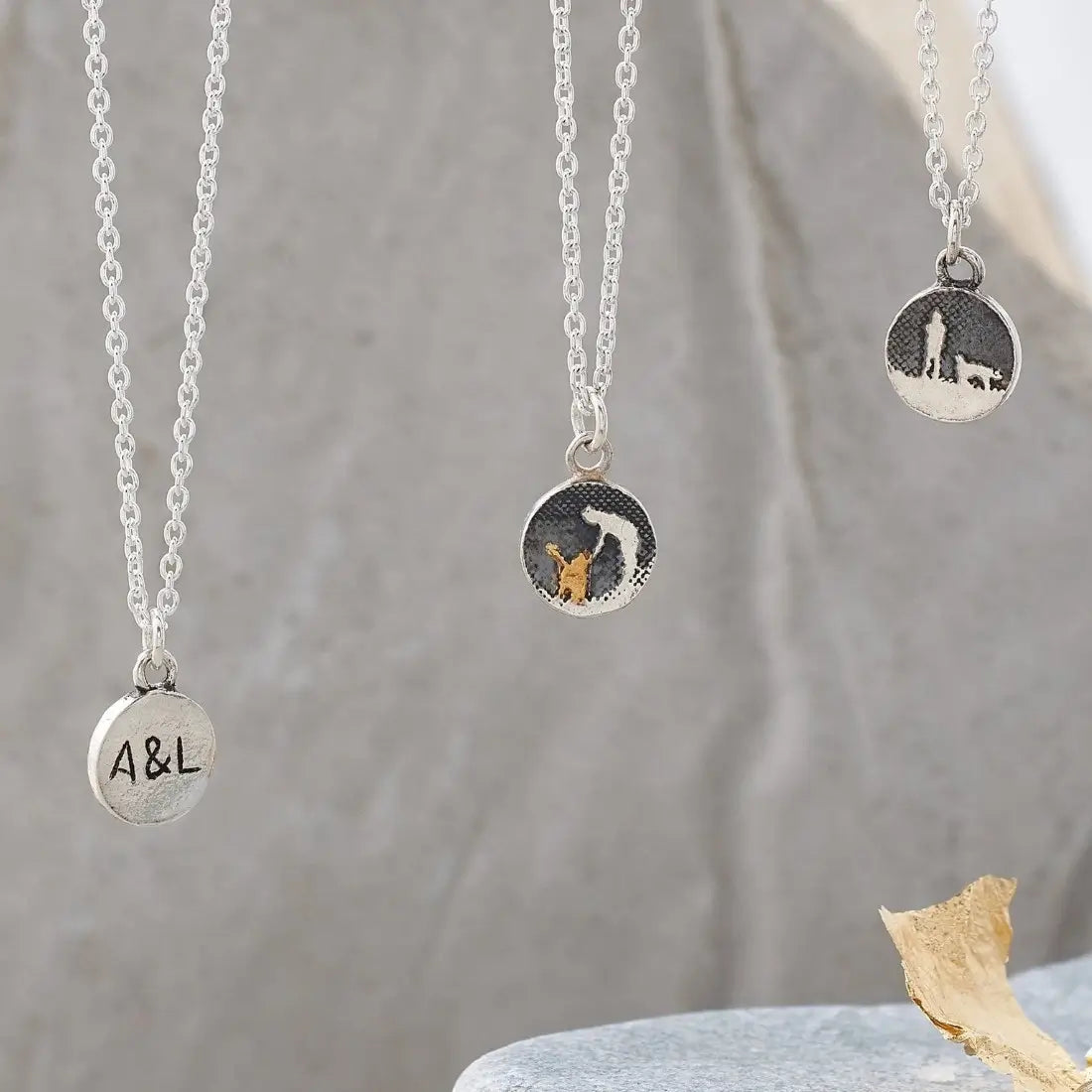 Lifestyle photo showing the Walks Under Night’s Sky Silver Dog Charm alongside two additional charms on a silver chain: a silver petting dog charm and a personalised charm engraved with A&L.