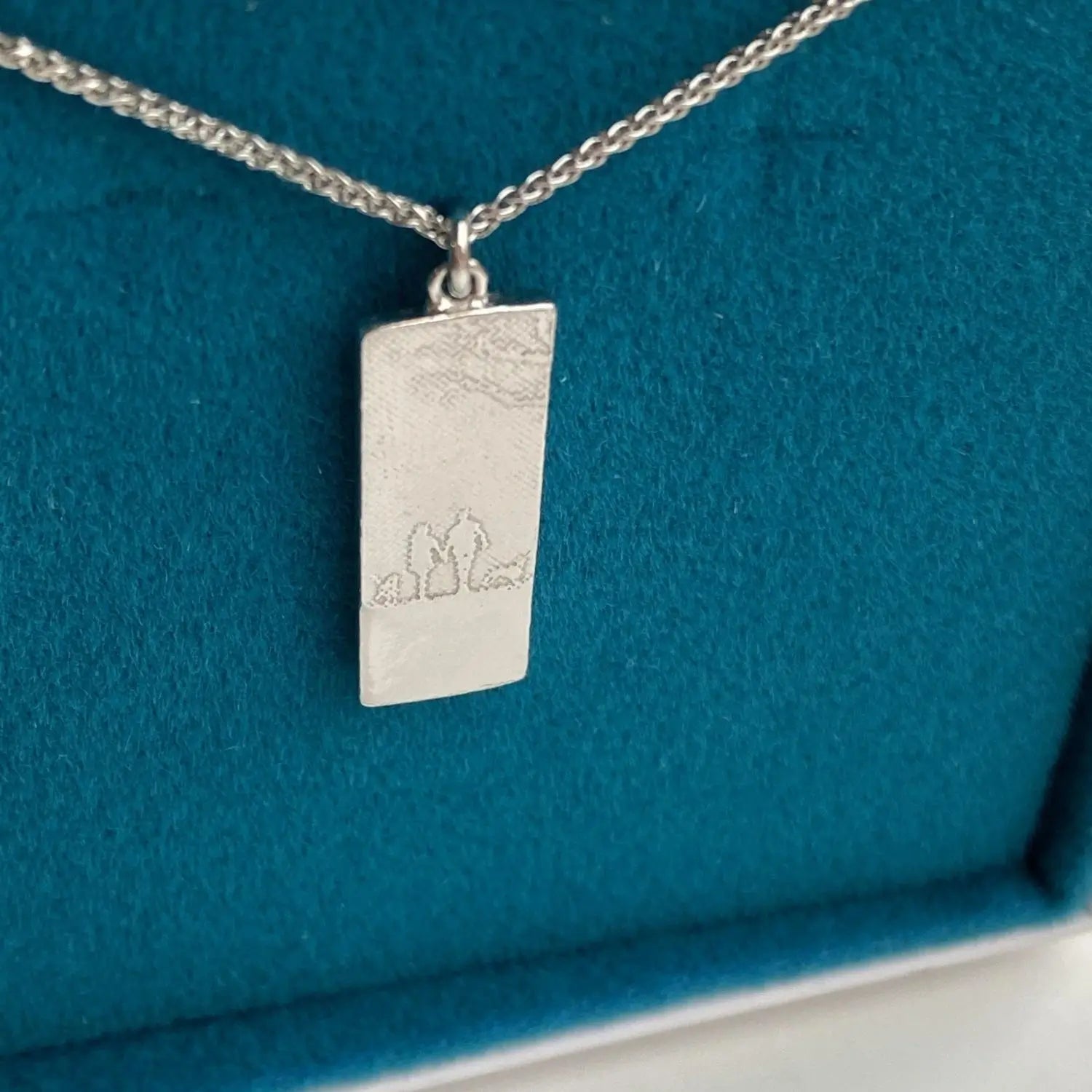White gold couple and two dogs necklace featuring an etched silhouette design, shown in its packaging.