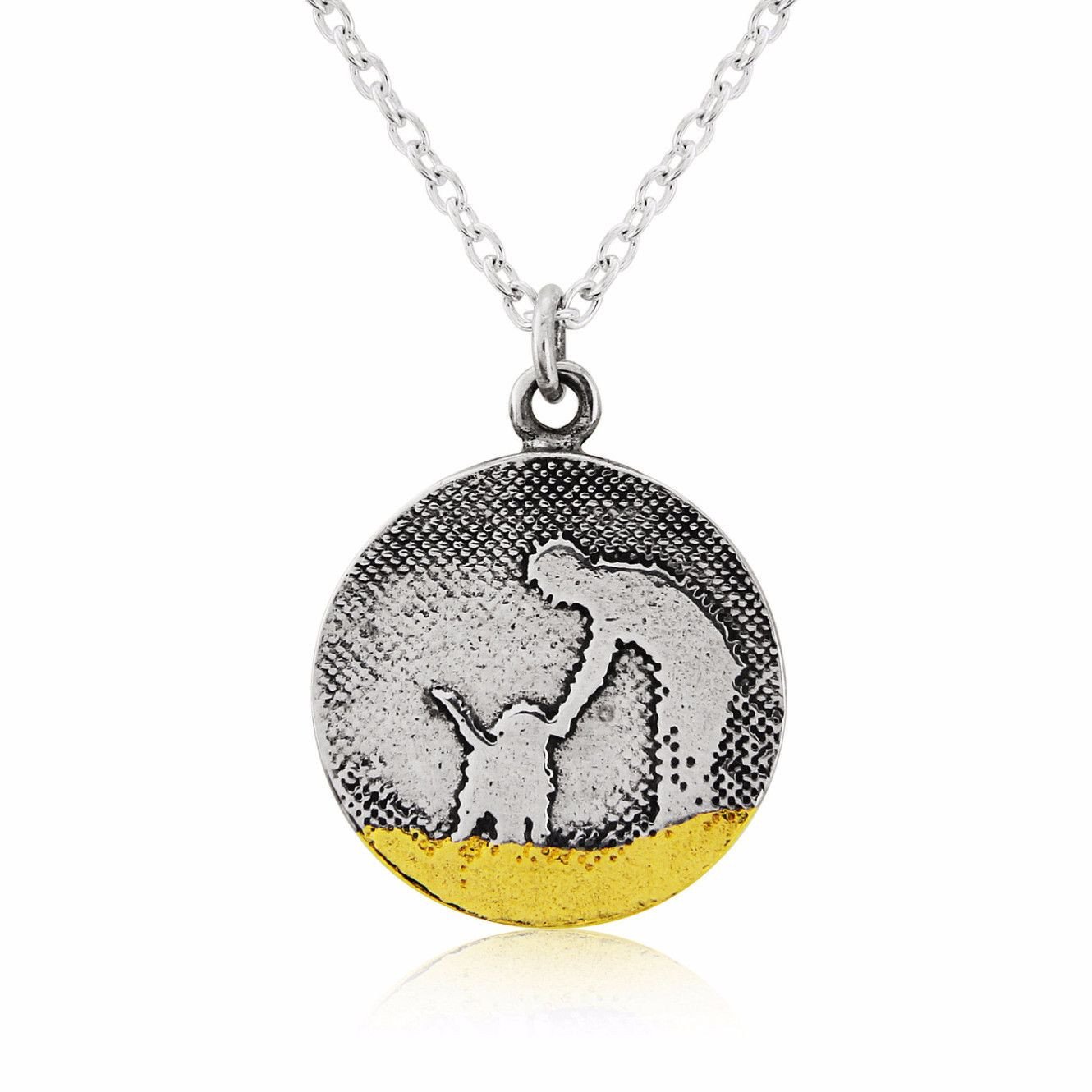 Round sterling silver dog lovers necklace showing an owner petting their dog along the beach, with oxidised detail and 22ct gold vermeil accents.