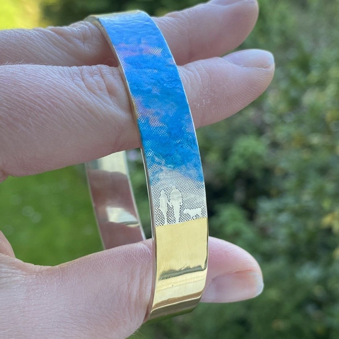 Blue Sky Memories Couple Bangle showing two figures  and a dog walking hand in hand beneath a blue enamel sky with gold‑vermeil sand detail.