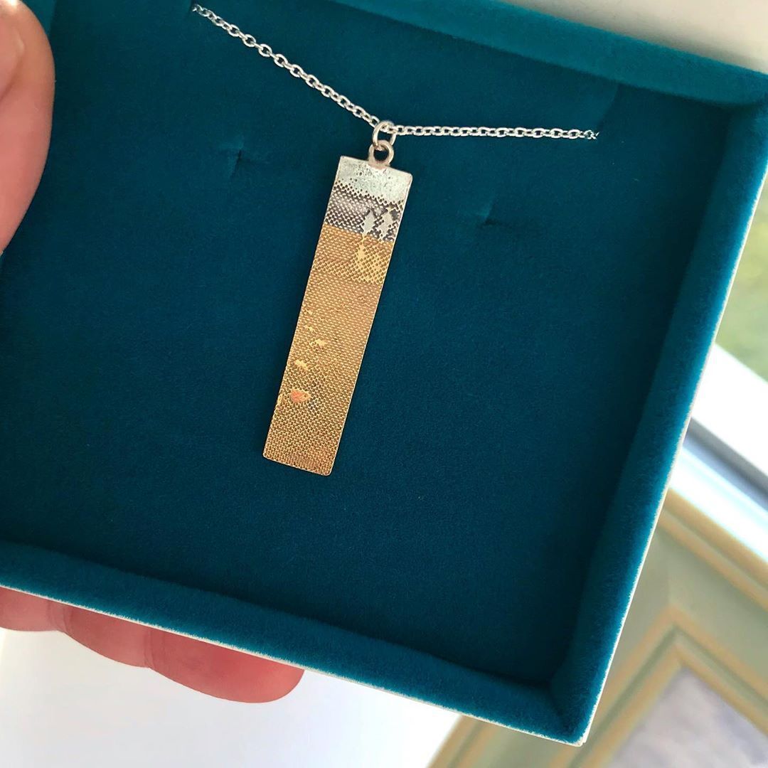 Footprints in the Sand Necklace displayed in blue gift box, showing the detailed beach silhouette and gold‑vermeil footprints.