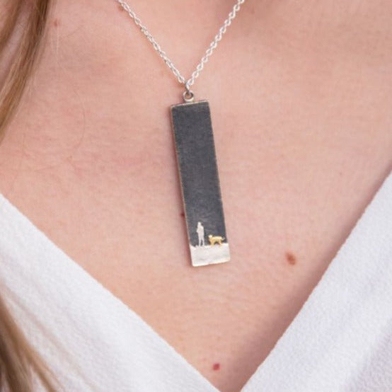 Model wearing the large Moonlight Sky Silver Dog Lovers Necklace showing the rectangular pendant with etched owner and dog beneath an oxidised moonlit sky.