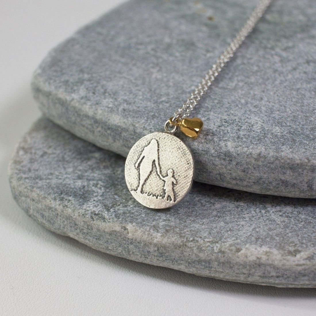 Lifestyle image of mother and child necklace with golden heart charm in sterling silver.