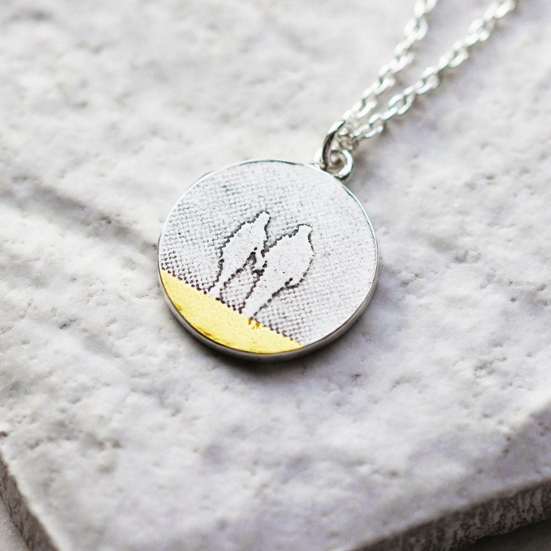 Round Beach Couple Necklace displayed on a natural background, showing the etched silhouette and polished silver finish.