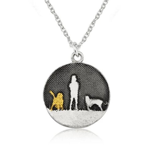 Sterling silver round two dog necklace showing a person walking their two dogs under the night sky in silhouette with a gold‑vermeil dog.