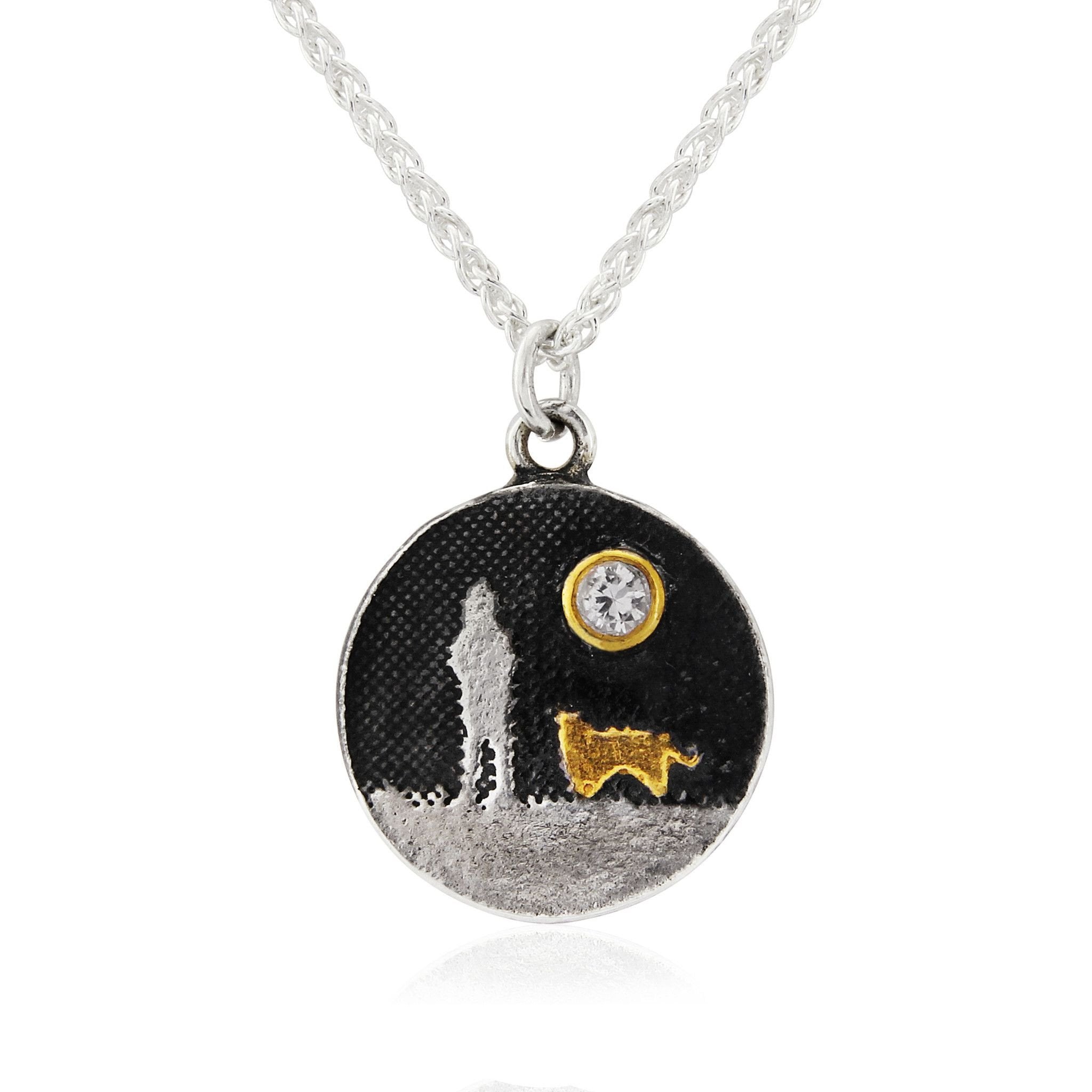 Round sterling silver dog lovers necklace featuring an etched dog silhouette beneath a white sapphire moon with gold‑vermeil dog detail.