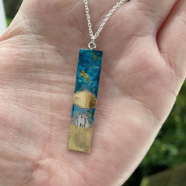 Sunset Couple Memory Necklace with blue enamel sky and 22ct gold vermeil details to highlight the sun and sand
