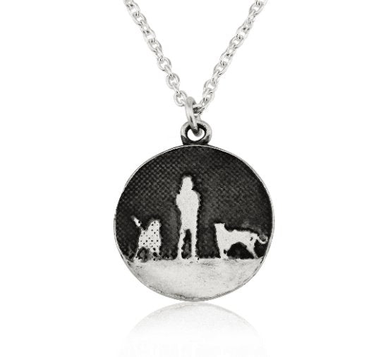 Sterling silver round necklace showing a person walking with two silver dog silhouettes under the night sky.